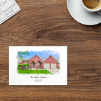 Postcard printed with a watercolor-style portrait of a red brick house with two garage doors, by a coffee cup