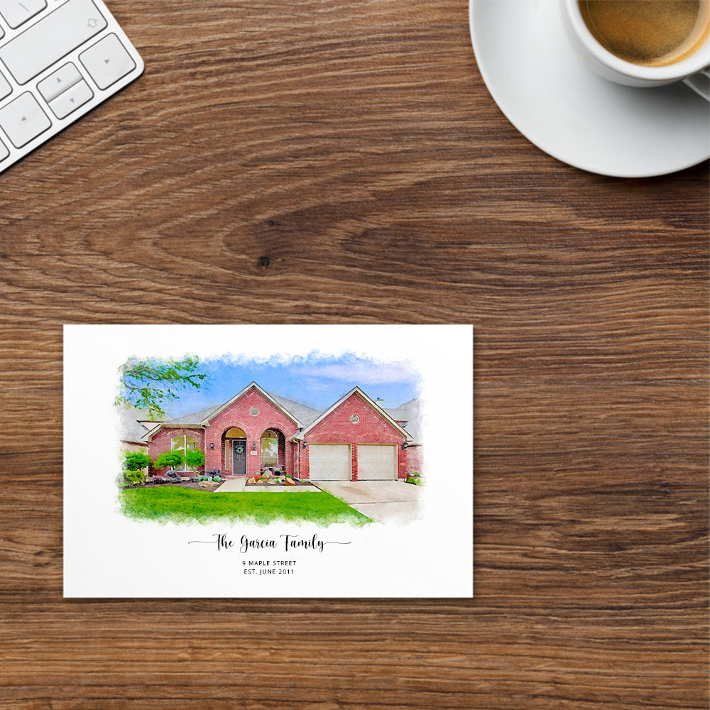 Postcard printed with a watercolor-style portrait of a red brick house with two garage doors, by a coffee cup