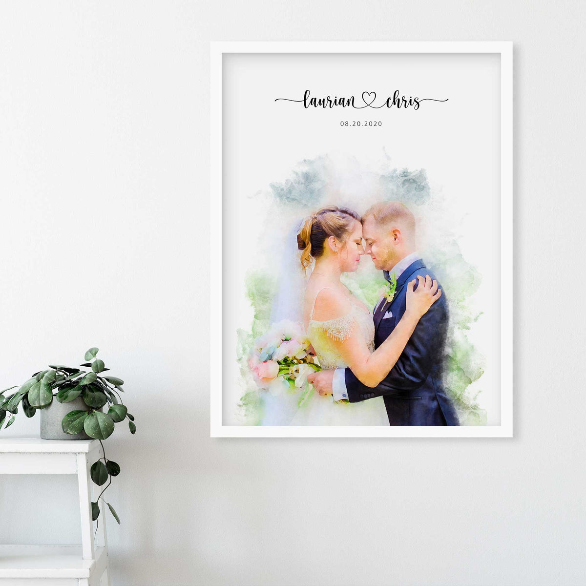 Watercolor-style portrait of a bride and groom embracing, in a white frame on a wall, with their names and a date above