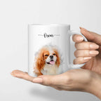 Hand holding a white mug printed with a watercolor-style portrait of a brown-and-white dog and the name 'Oscar'